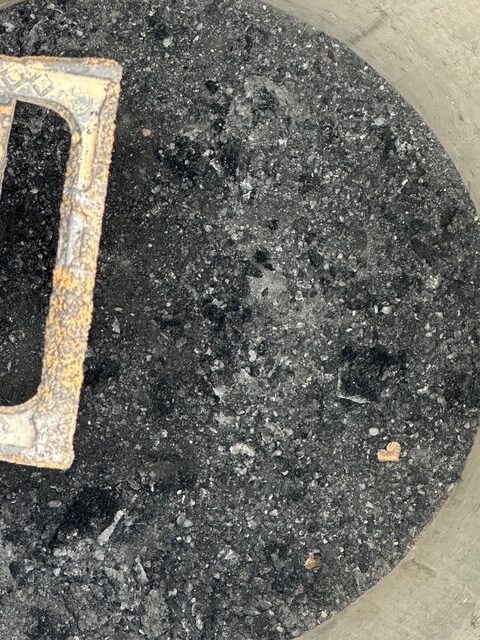 Charred surface with metal object corner visible.